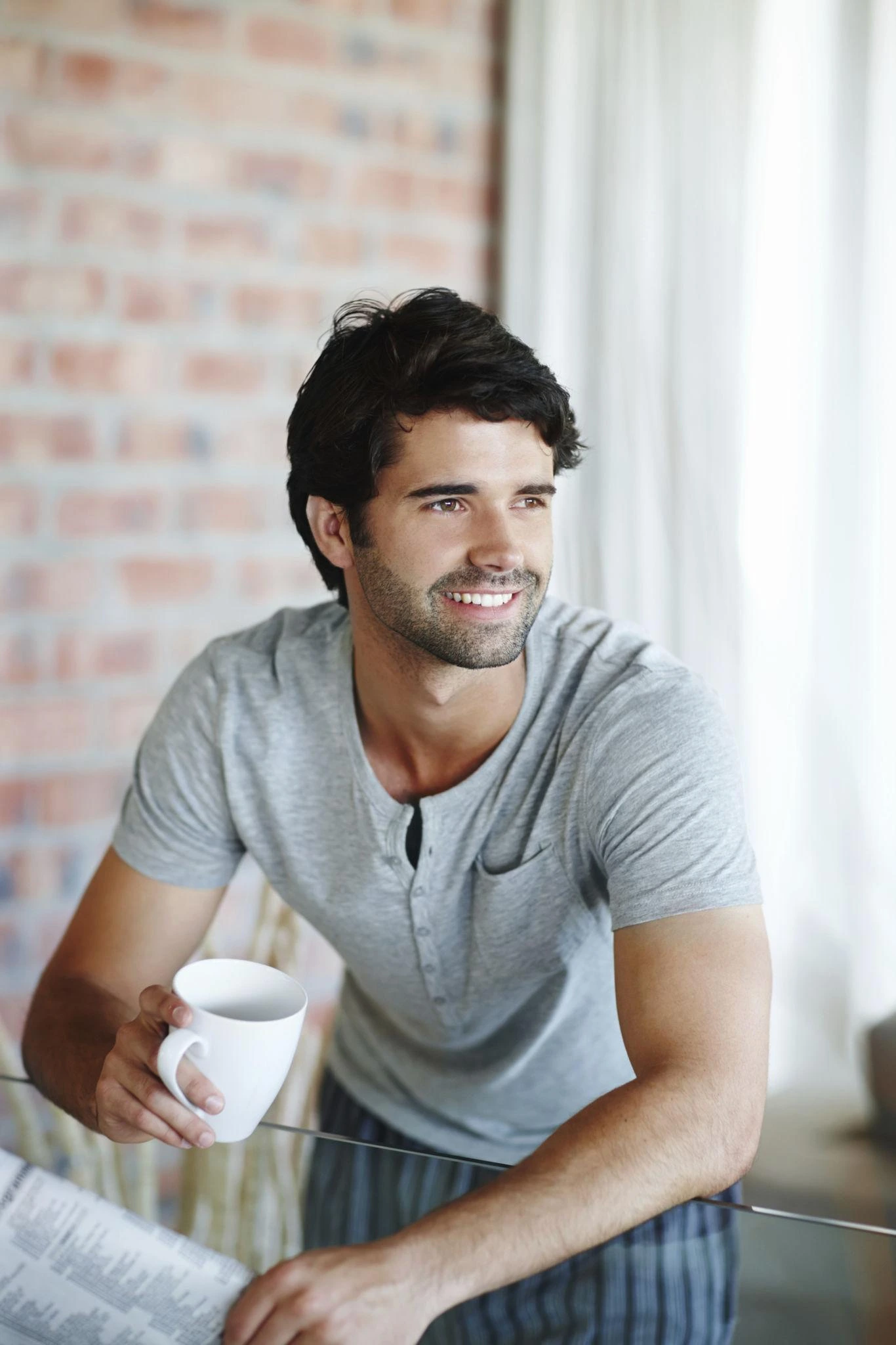man smiling in pajamas holding coffee after a good night of sleep
